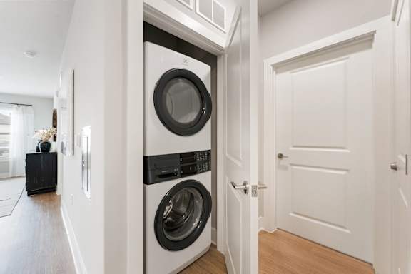 A modern laundry room with a washer and dryer built into the wall at The Hendry Apartments, Fort Myers, FL