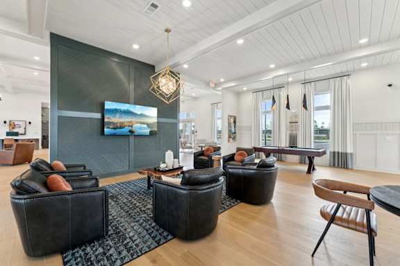 A living room with a large screen tv and a wooden floor at The Hendry Apartments, Florida