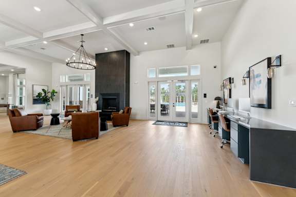 A modern living room with a fireplace and a kitchen area in the background at The Hendry Apartments, Fort Myers