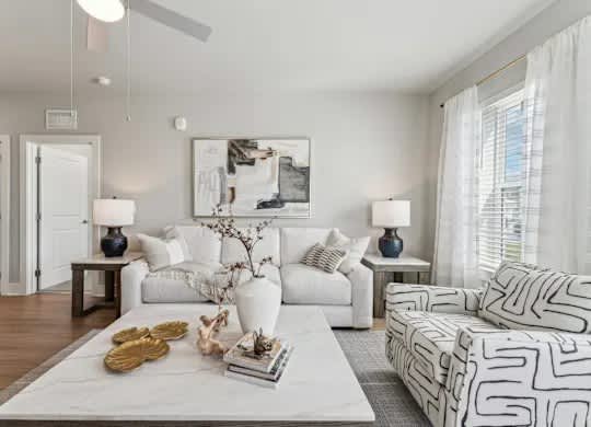 A living room with a white couch, a white coffee table, and a white rug.