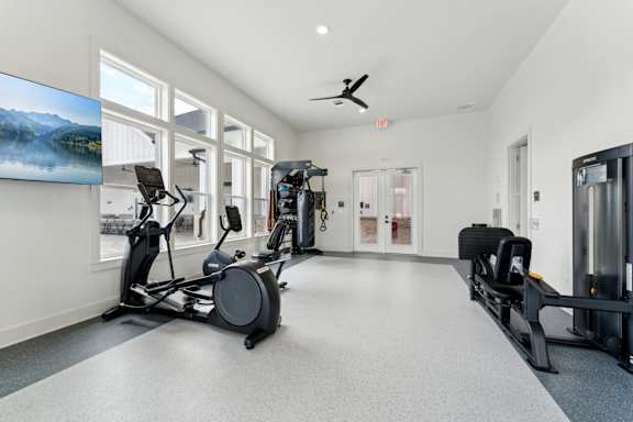 A spacious gym with a variety of equipment including treadmills, stationary bikes, and weight machines at The Hendry Apartments, Fort Myers