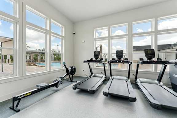 A room with treadmills and a view of the outdoors through the windows at The Hendry Apartments, Florida