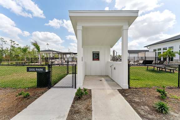 A white dog park pavilion with a black fence and gate at The Hendry Apartments, Florida