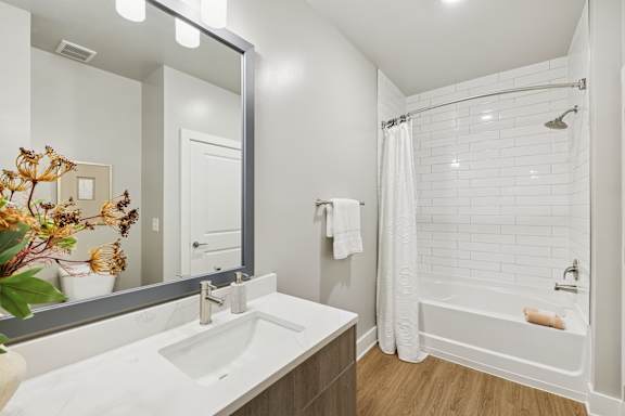 A white sink in a bathroom with a white tub and a white shower curtain.
