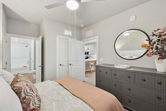 A bedroom with a bed, dresser, mirror, and a ceiling fan.