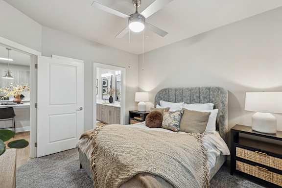 A bedroom with a bed, nightstand, and a ceiling fan.