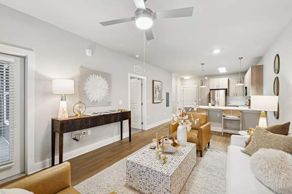 A modern living room with a white ceiling fan and a large mirror on the wall.