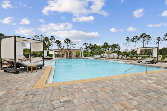 A large outdoor swimming pool surrounded by lounge chairs and umbrellas at The Beacon at 331 Apartments, Santa Rosa Beach, FL