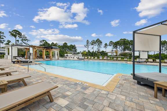 A pool with a sun lounger and a shade structure at The Beacon at 331 Apartments, Santa Rosa Beach, FL