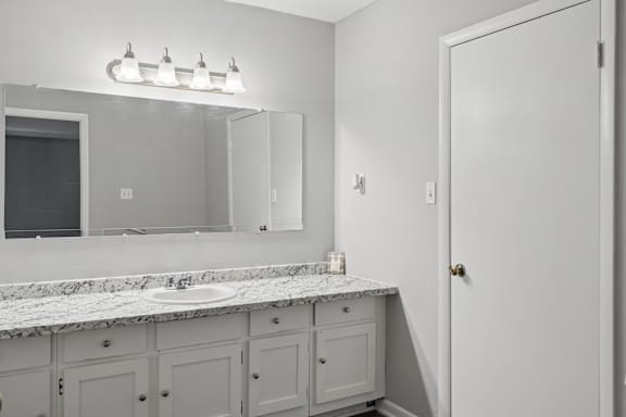 A bathroom with a marble countertop and a large mirror above it.