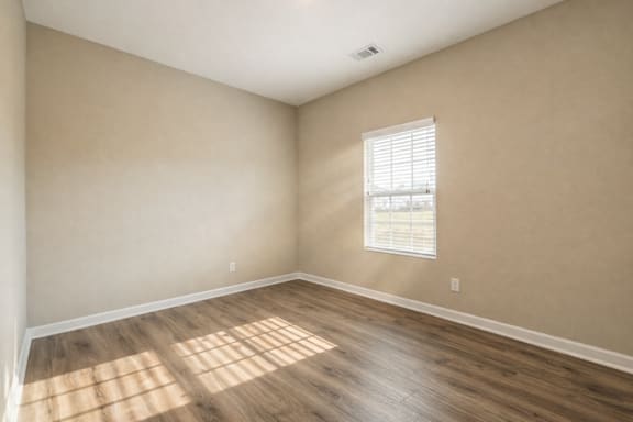 Room with wooden floors and a window with blinds at Club Villas Apartments, Kathleen, GA