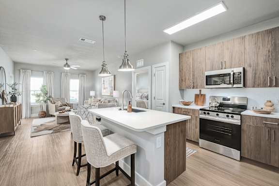 Floor Plan  A modern kitchen with a white island and wooden cabinets.at The Ashton at East Park Apartments, Kennesaw, Georgia
