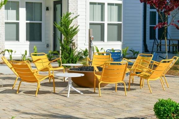 Outdoor yellow chairs around a fire pit on a patio at The Eddy at Riverview, Smyrna, 30126