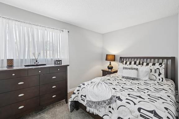 A bedroom with a bed, nightstand, and dresser.