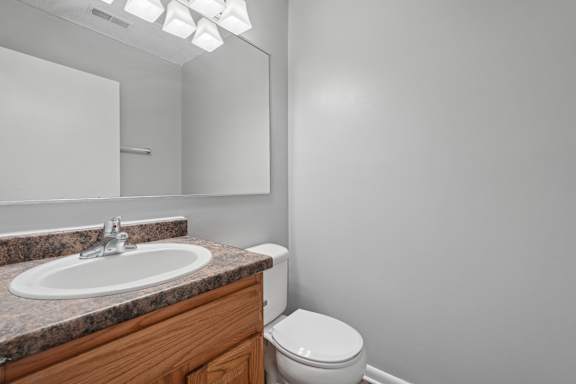 A bathroom with a toilet, sink, and mirror.