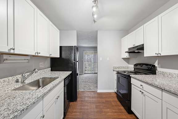 A kitchen with black appliances and white cabinets.