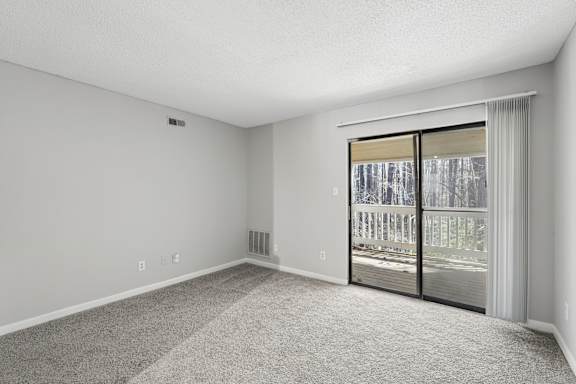 A room with a sliding glass door leading to a balcony.