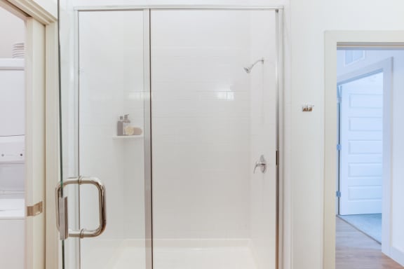 a shower with a glass door in a white bathroom