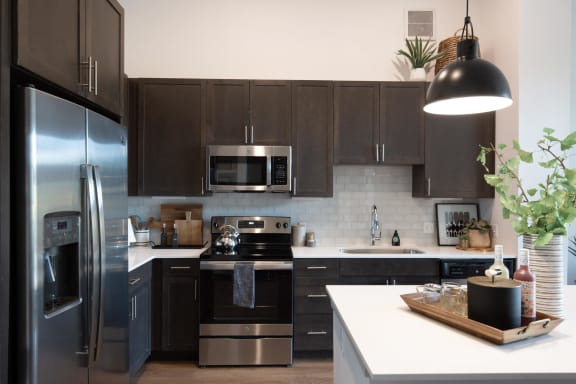 a modern kitchen with stainless steel appliances and dark cabinets