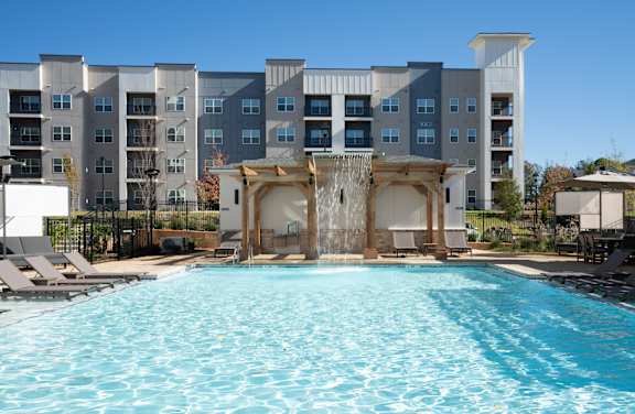 A large swimming pool in front of a multi-story apartment building at The Delaney at East Park Apartments, Georgia