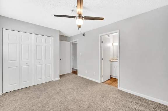 A room with a ceiling fan and carpeted floor.