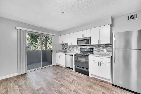A kitchen with stainless steel appliances and white cabinets.