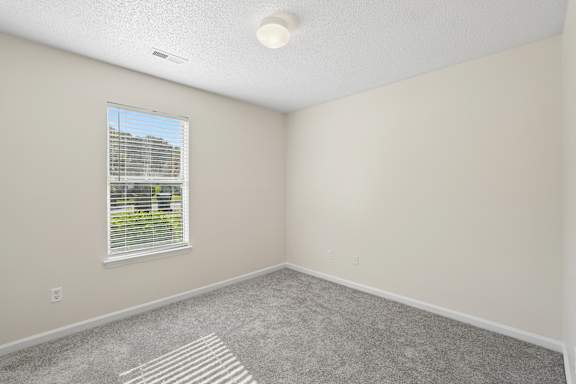 A room with a window and a striped rug on the floor.