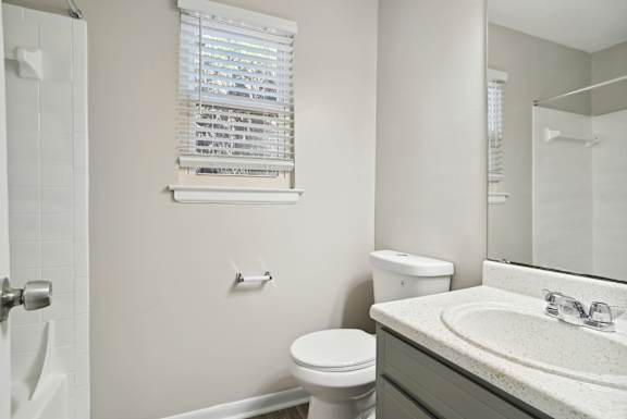 A bathroom with a toilet, sink, and mirror.