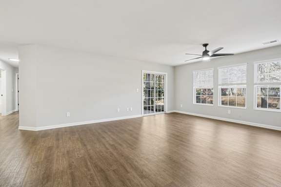 A spacious room with a ceiling fan and wood flooring.