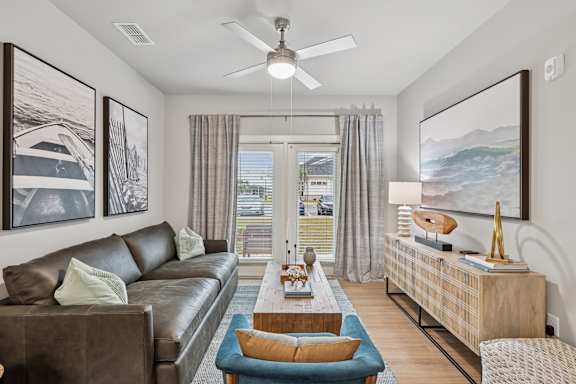 A living room with a brown leather couch, a blue chair, and a wooden coffee table.