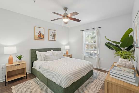 A bedroom with a bed, nightstand, and a ceiling fan.