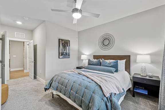A bedroom with a bed, nightstand, and a ceiling fan.