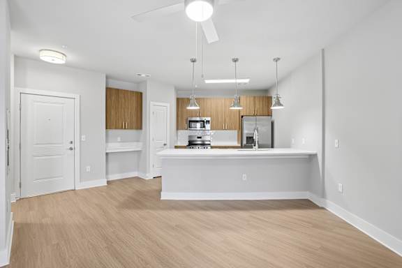 A kitchen with a white ceiling fan and wooden cabinets.