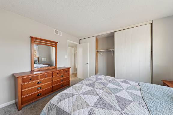 A bedroom with a bed, dresser, and mirror.