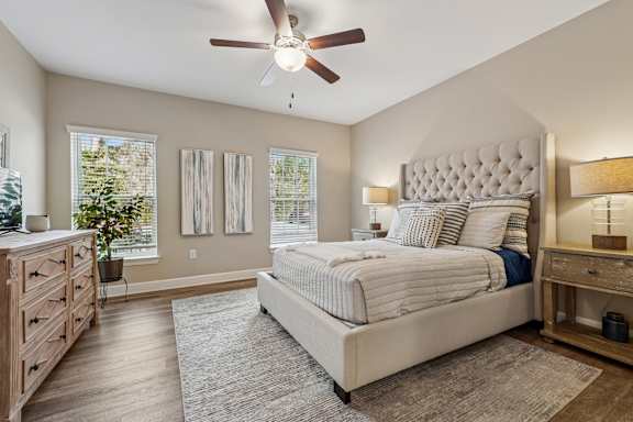 A bedroom with a large bed, a dresser, and a ceiling fan.