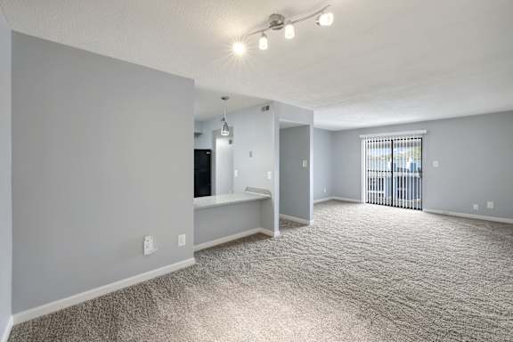 A spacious room with a carpeted floor and a window with bars on it.