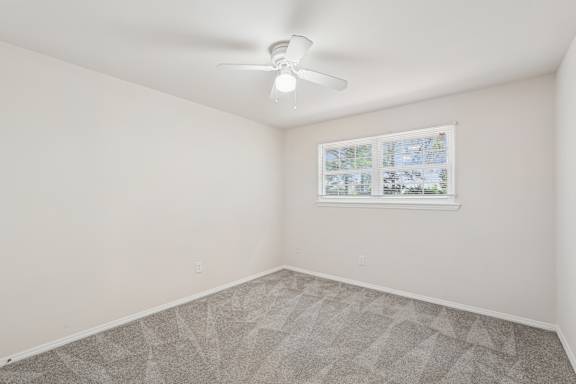 A room with a ceiling fan and a window with a view of a map.