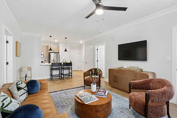 A living room with a brown couch, a brown chair, a coffee table, and a ceiling fan at Union Eleven Apartments, Atlanta, GA 30324