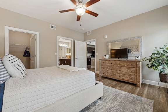 A bedroom with a large bed, a dresser, and a ceiling fan.