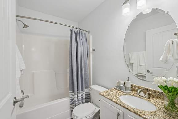 A white bathroom with a toilet, sink, and shower.