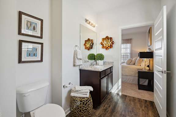 a bathroom with a toilet and a sink in a room with a bedroom