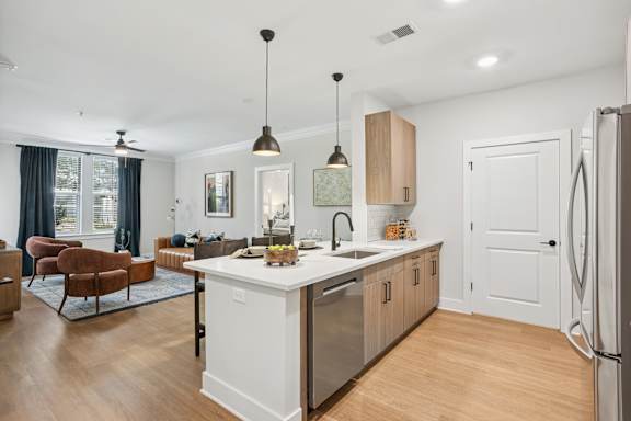A modern kitchen with a white fridge and wooden cabinets at Union Eleven Apartments, Georgia 30324