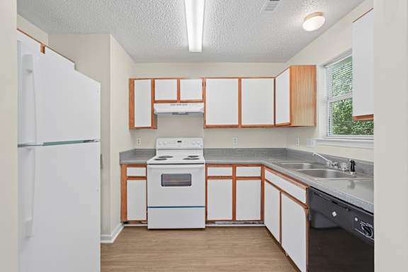 A kitchen with a white refrigerator and wooden cabinets.