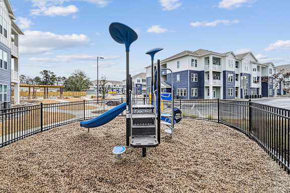 A playground with a blue slide and a black fence.