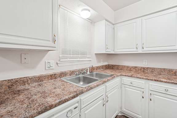 Floor Plan  A kitchen with white cabinets and a granite countertop.