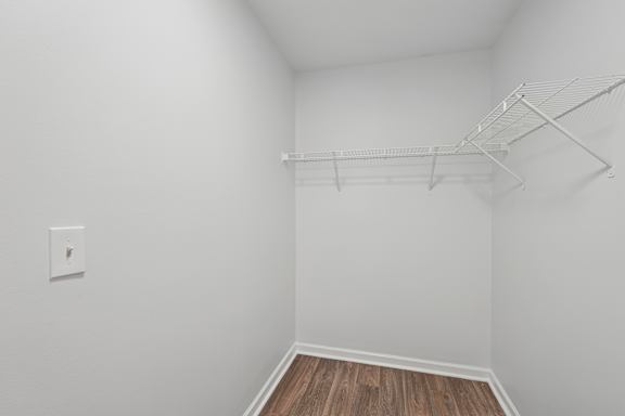 A white wall with a light switch and a white shelf.