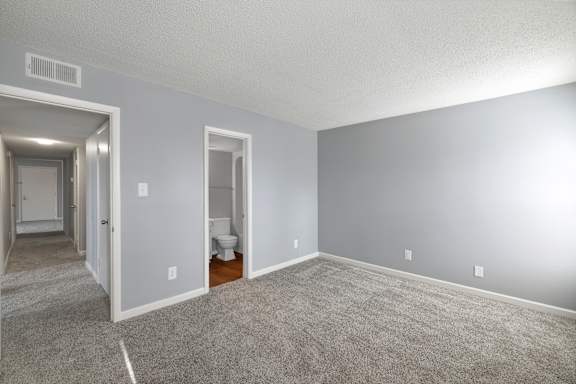 A room with a carpeted floor and a toilet in the corner.