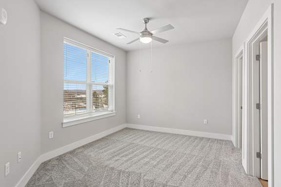 A room with a ceiling fan and a carpeted floor.
