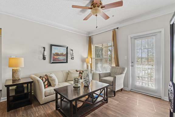 A living room with a white couch, a coffee table, and a ceiling fan.