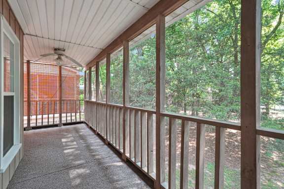 A balcony with a ceiling fan and a view of trees.